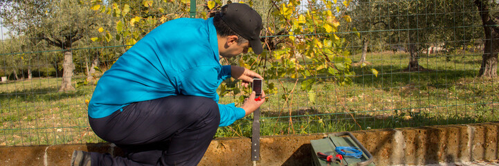 Image of an electrician assembling and repairing the photocell sensor of an automatic gate in a driveway. Handyman at work. Horizontal banner 
