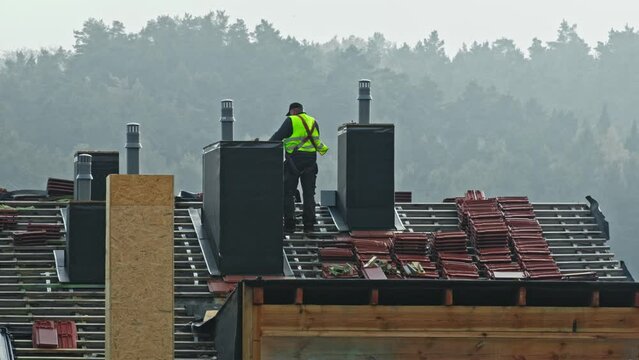 Professional Roofer Carpenter Standing on Roof of Building Under Construction
