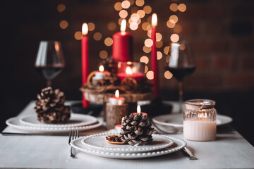 Rustic table decor for Christmas or New Year family dinner. Centrepiece with red candle, dry orange, cone, cinnamon, anise. Zero waste eco-friendly home. Cozy atmosphere, dark background. Close up