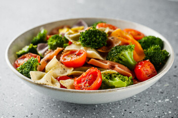 delicious colored farfalle pasta on a stone background