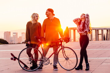 Group of friends walking outdoors with a bike and skateboard