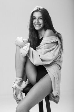 Young adult woman sitting on a stool in a photography studio.