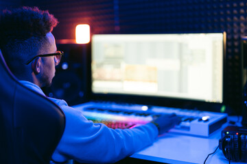 Producer, audio engineer uses a control panel and screen to record a track of a new album in a...