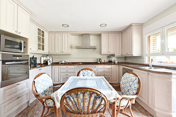 A kitchen with wooden furniture clearly arranged in a u along the entire room with a dining table in the center