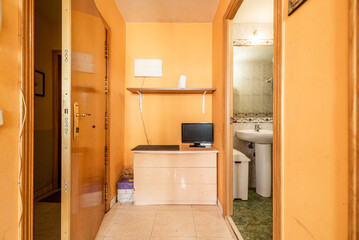 Hallway of a messy house with access to a bathroom with white porcelain toilets
