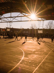 children playing basketball against the light, on a sunny day, with the sun in yellow background