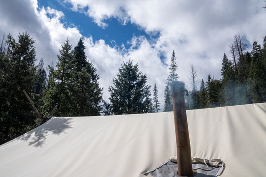 Smoke Rises From A Chimney On A Tent For Ventilation From The Camp Stove Inside The Tent, Staying Warm During Winter Camping