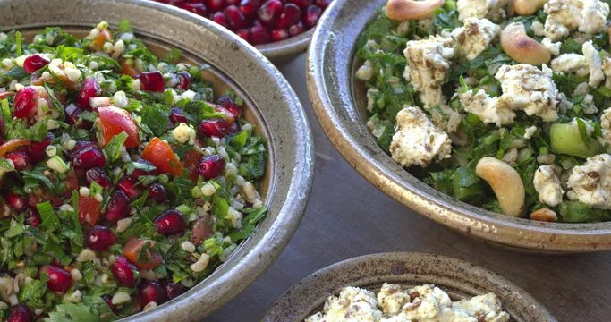 Two parsley salads: tabbouleh like barley and parsley salad with feta and cashew nuts and classic tabbouleh with pomegranate. Table spin. 