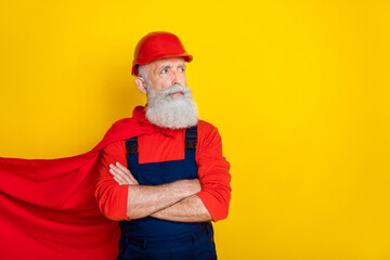 Photo of serious confident old guy dressed uniform overall red hardhat mantle arms folded looking empty space isolated yellow color background