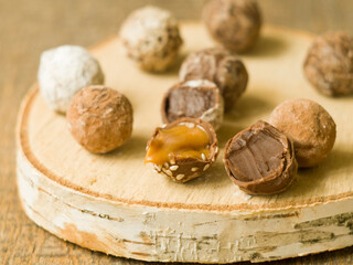 Homemade chocolate candy truffles glazed with chocolate ganache on a wooden board, closeup view