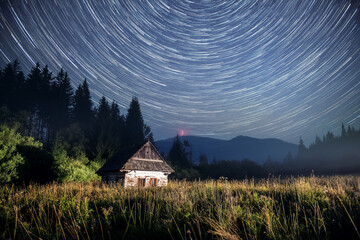 Startrails over the Kralova Hola, Chamkova Stodola, Starry night and Old Wooden Hut in the Mountains. © Filip