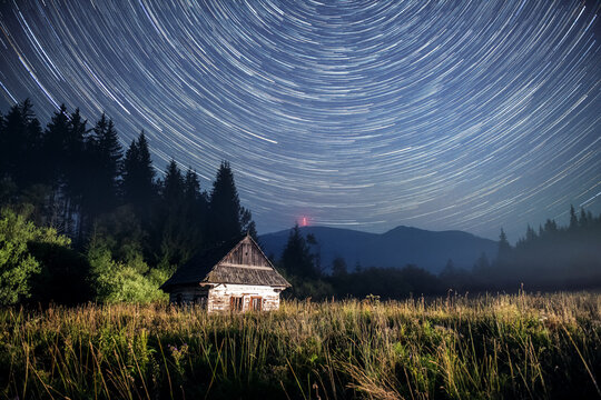 Startrails over the Kralova Hola, Chamkova Stodola, Starry night and Old Wooden Hut in the Mountains.