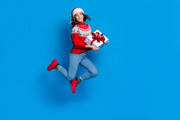 Full length photo of funny sweet lady wear ornament sweater jumping high holding xmas gifts empty space isolated blue color background