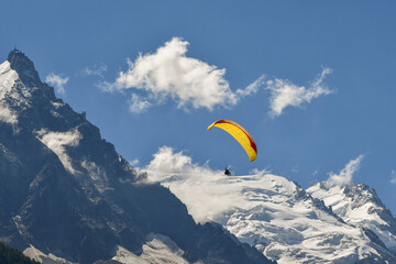 A yellow paraglider flying in front of Mont Blanc mountain in the French Alps in summer,...