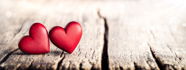 Two Red Hand Carved Wooden Hearts On Rustic Table With Sunlight And Bokeh - Valentines Day
