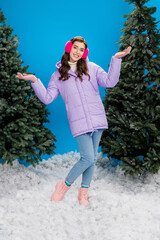 Vertical portrait of cheerful attractive girl wear outerwear clothes ear warmers stand snow isolated on blue color background © deagreez