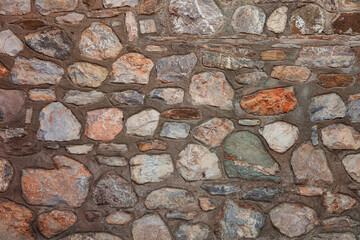 Stonewall background with heavy use of cement. Stonewall made of coloured stones