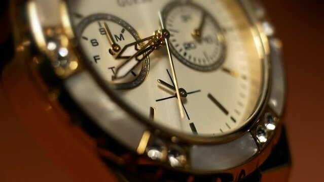  Clock hands in motion on the dial clock face of a gilded gold plated mechanical quartz chronometer watch close-up macro. Running of time and life