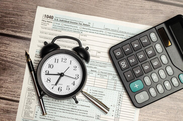 Top view tax form 1040 with pen, calculator and black alarm clock. tax time. financial document.
