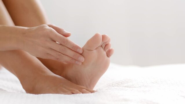 Feet care. Close up shot of female legs, unrecognizable woman rubbing caring cream on her feet soles, empty space