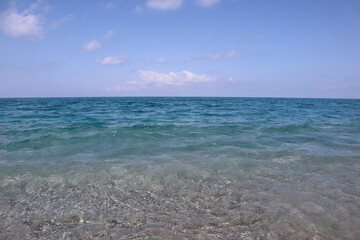 Sea with transparent water and blue sky with clouds on a sunny day, background image