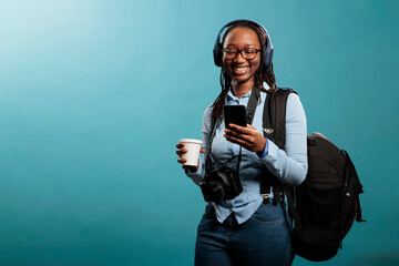 Joyful professional photographer with wireless headphones and modern smartphone listening to music...