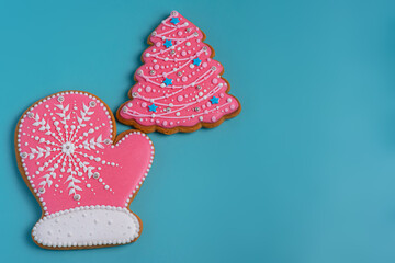 New Year's goodies. Christmas mitten gingerbread pink and a Christmas tree on turquoise background.