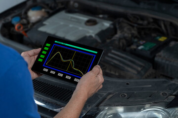 MECHANIC MAKING DIAGNOSIS AND MAINTENANCE TO A CAR IN THE WORKSHOP USING DIGITAL TABLET. NEW TECHNOLOGIES
 IN REPAIRING VEHICLE BREAKDOWNS.