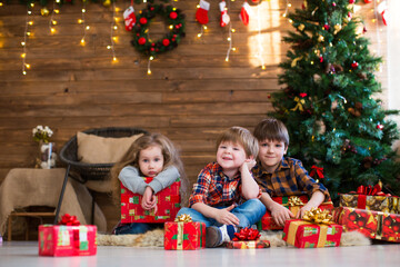Fototapeta na wymiar Children with New Year's gifts on the background of the Christmas tree sitting on the floor
