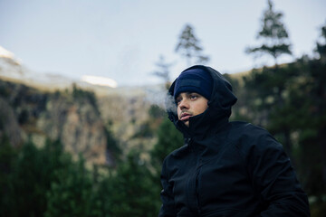 Boy with coat and hat smoking a marijuana cigarette in nature