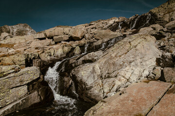 Waterfall running down some mountain rocks during a clear day