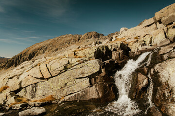 Waterfall running down some mountain rocks during a clear day