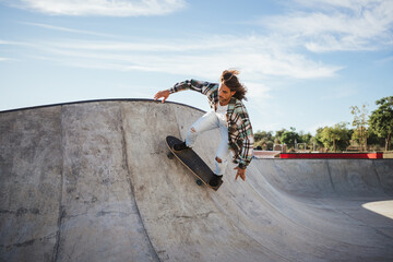 Professional man going up a wall of a skate park pool while skateboarding with surfskate