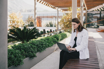 Young woman freelancing with a laptop in the park.