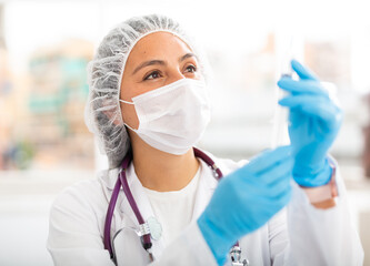 Experienced female health worker working in the clinic prepares a syringe for injection in the treatment room. Close-up ..portrait