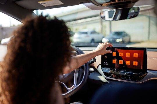 Young Woman Touching Screen Of Media Player Sitting In Electric Car