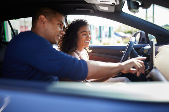 Smiling couple using GPS while sitting in electric car