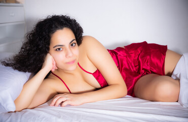 Naklejka premium Portrait of long-haired brunette woman in lingerie enjoying lying in bed