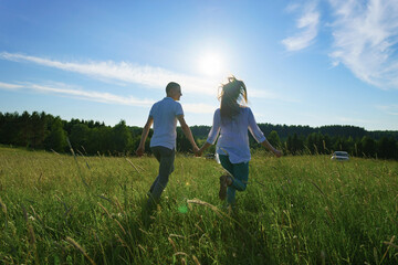 Young couple walking through green field