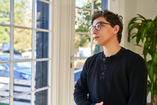 Man In Sunny Room In House Looking Out Window