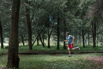 Obraz premium Adult Latino man running through the woodsmountain,