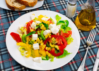 Popular all over the world appetizing vegetable salad made of tomatoes, Feta cheese, lettuce leaves, canned corn and pepper