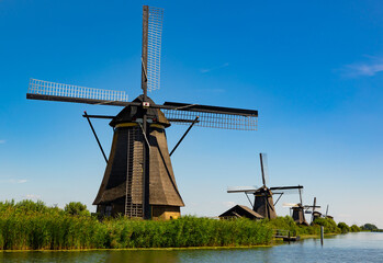 Fototapeta na wymiar System of ancient windmills used for draining water from Kinderdijk polder soil into river, Netherlands