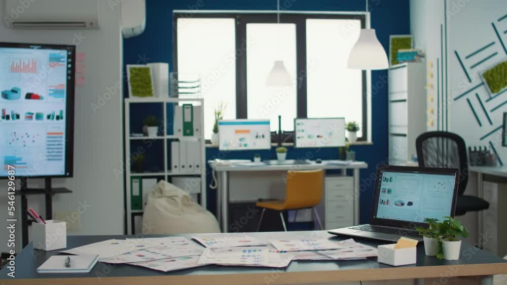Poster empty startup office with laptop showing analytics on display with moving charts and tv wall screen 