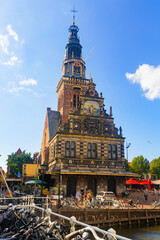 Obraz premium Picturesque summer view of green and blooming Alkmaar cityscape along Mient canal overlooking tower of Waag building on square Waagplein on sunny day, Netherlands