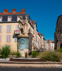 Summer view of Riom cityscape overlooking fountain erected in honor of General Desaix with...