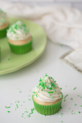 Vanilla Cupcakes with Buttercream Frosting and Green Sprinkles on White Kitchen Counter