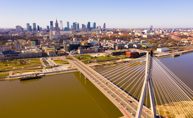 Aerial view of Warsaw current urban landscape on bank of Vistula and Swietokrzyski Bridge over river on sunny day, Poland