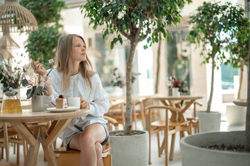 Attractive girl drinking tea with cake in cafe