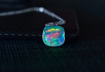 Opal is an opal pendant necklace placed on the ground.
